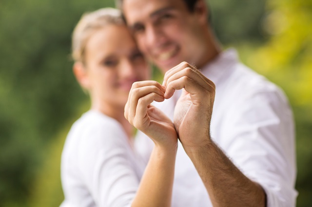 young couple making heart with hands
